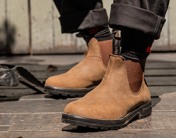 Brown Hard Yakka Brunswick Dealer Boots on a wooden floor with a neutral background.