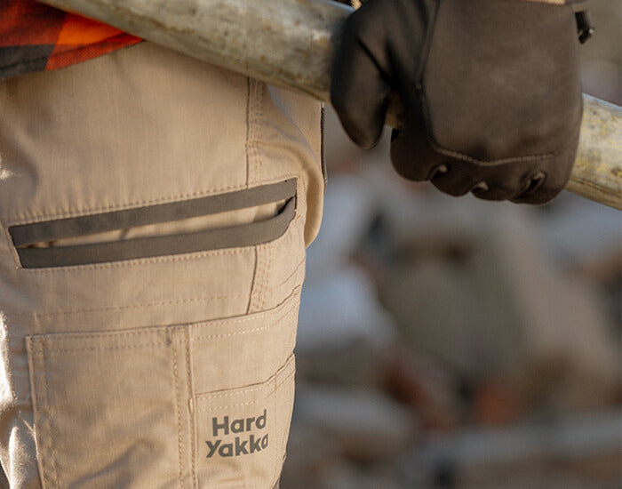 Person wearing khaki Hard Yakka trousers, holding a metal rod.