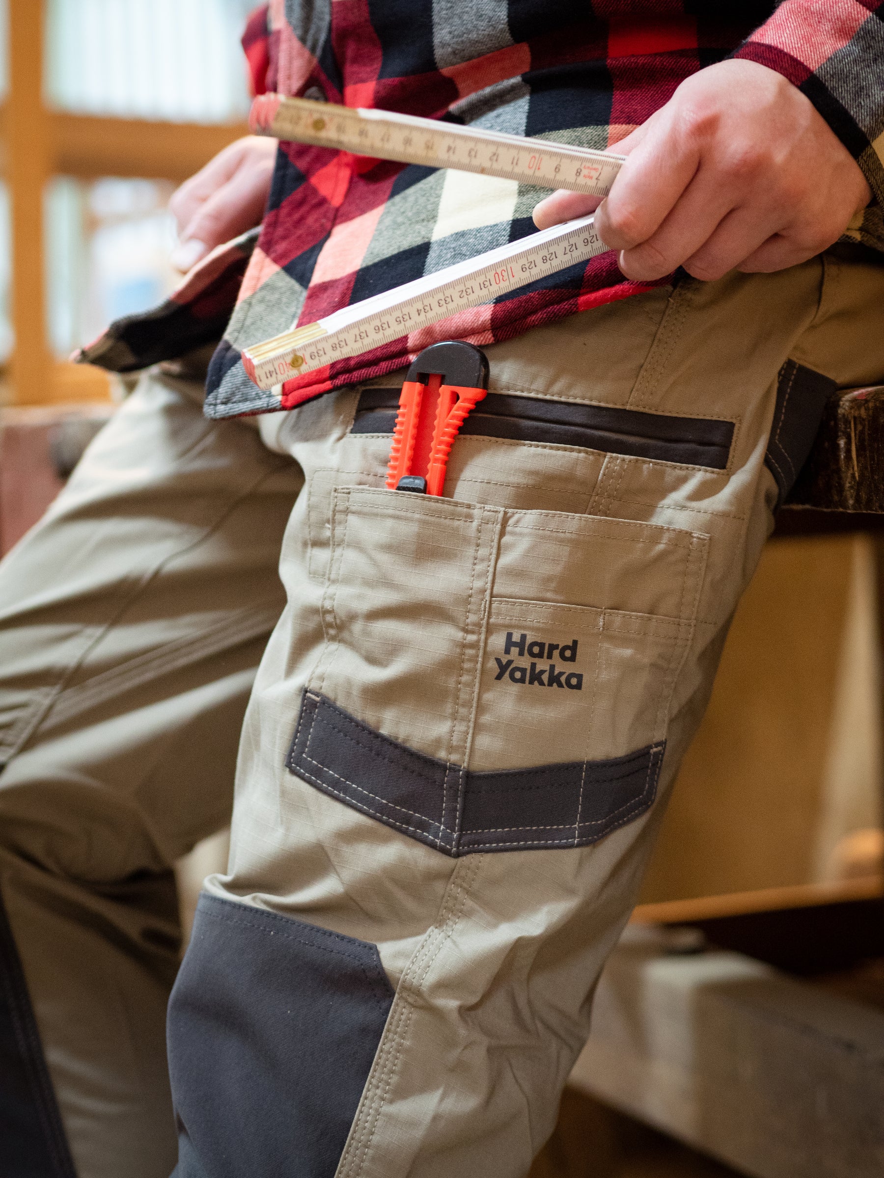 Person holding a tape measure, wearing a pair of Hard Yakka trousers